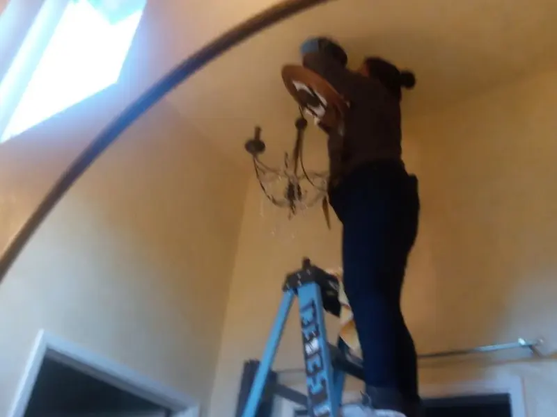 Electrician installing a chandelier in a Buffalo residence